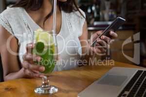 Woman using mobile phone at bar
