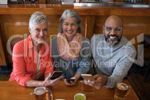 Senior friends using mobile phone in bar