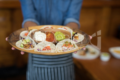 Waiter holding plate of mexican food in bar