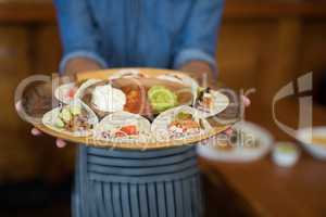 Waiter holding plate of mexican food in bar