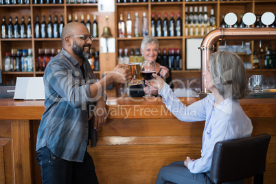 Friends toasting glass of drinks at counter in bar