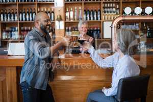 Friends toasting glass of drinks at counter in bar