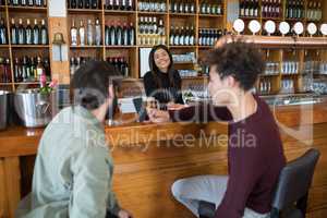 Waitress standing at counter while two men using mobile phone