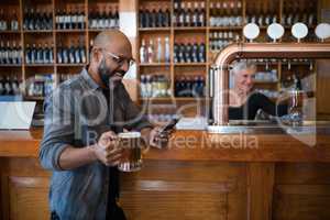 Man using mobile phone while having glass of beer in bar