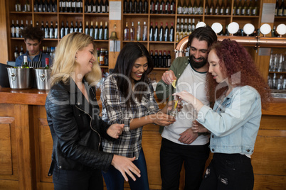 Friends having tequila shot at counter in bar