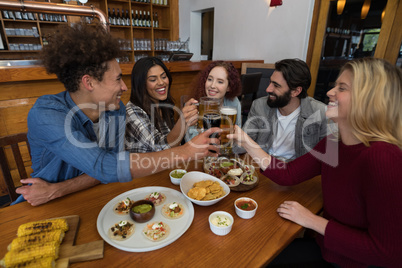 Friends toasting glass of beer in bar