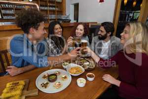 Friends toasting glass of beer in bar