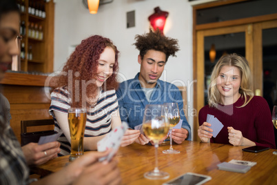 Happy friends playing cards while having glass of beer