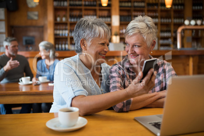 Smiling senior friends using mobile phone