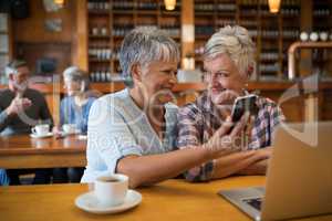 Smiling senior friends using mobile phone