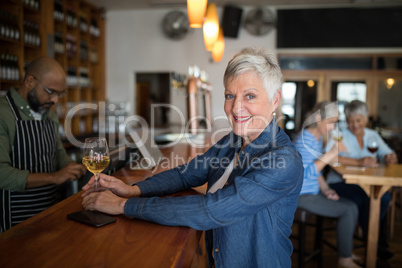 Smiling senior woman having glass of wine at counter