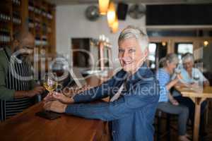 Smiling senior woman having glass of wine at counter