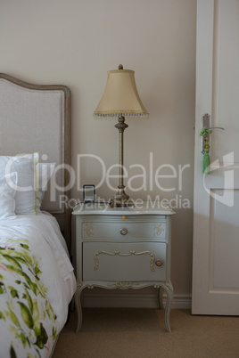 Lamp on wooden bedside table in bedroom