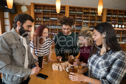 Friends playing with wooden blocks while having glass of beer