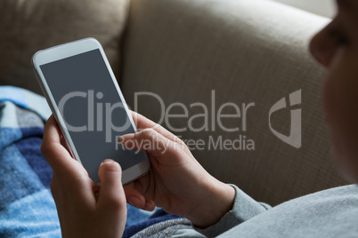 Woman using mobile phone on sofa in living room