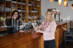 Portrait of waitress and beautiful woman standing at bar counter