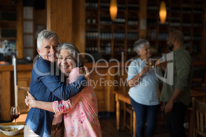 Two senior female friends embracing each other