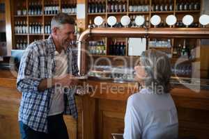 Two friends having glass of beer at counter in restaurant