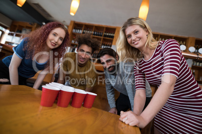 Smiling friends standing near beer pong on table
