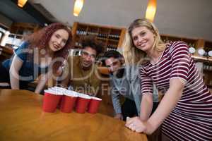 Smiling friends standing near beer pong on table