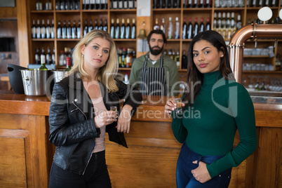 Female friends holding tequila shot at counter