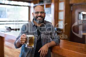 Happy man holding glass of beer in bar