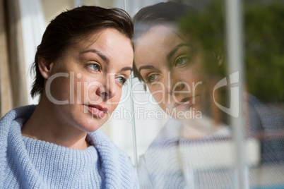 Thoughtful woman looking through window