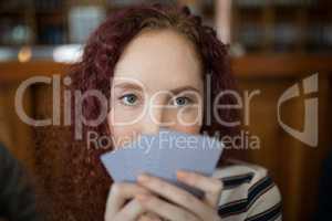 Beautiful woman holding cards in bar