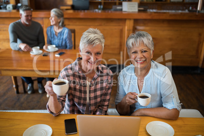 Smiling senior friends having cup of tea in restaurant