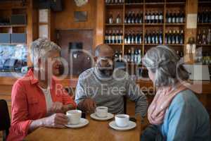 Happy friends interacting while having cup of coffee