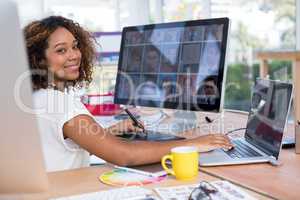 Female executive working over graphic tablet at her desk in office