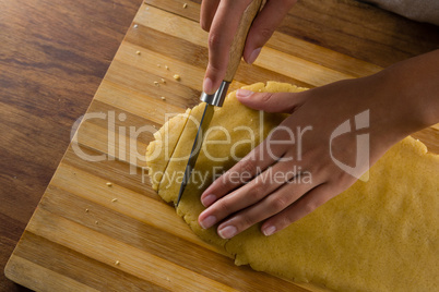 Woman slicing dough on chopping board