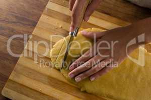 Woman slicing dough on chopping board