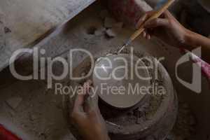 Female potter molding a bowl with hand tool