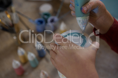 Hands of boy decorating mug with paint