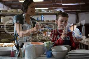 Female potter and boy painting bowl