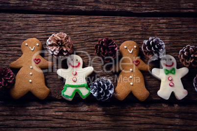 Gingerbread cookies and pine cone arranged on wooden table