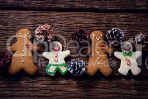 Gingerbread cookies and pine cone arranged on wooden table