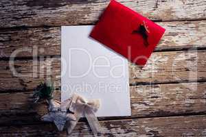 Red envelope, blank paper and christmas decorations on wooden plank