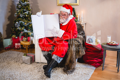 Santa Claus showing a book in living room