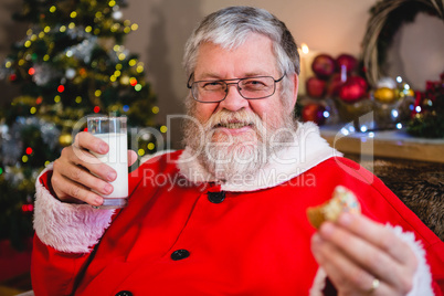 Santa Claus having christmas cookie with glass of milk