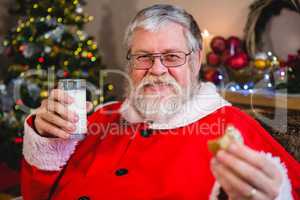 Santa Claus having christmas cookie with glass of milk
