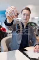 Salesman showing car key while sitting in showroom
