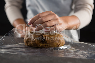 Woman wrapping dough in a plastic wrap