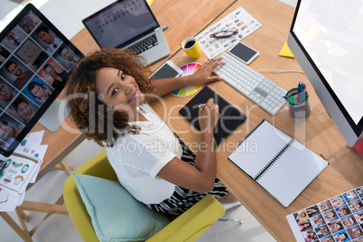 Female executive working over graphic tablet at her desk in office