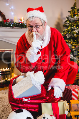 Santa claus with finger on lips in living room during christmas time