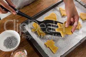 Man placing gingerbread cookies in baking tray