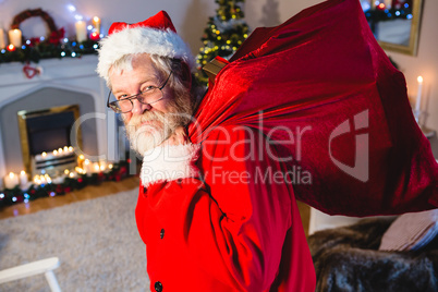 Portrait of santa claus holding gift sack at home