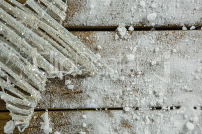 Cropped image of star shape decoration amidst artificial snow