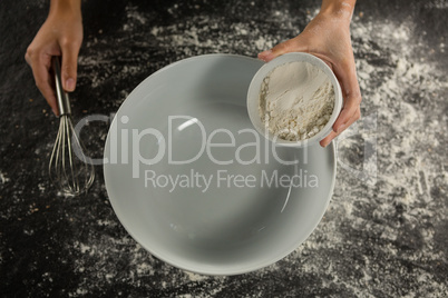 Woman holding whisk and bowl with flour